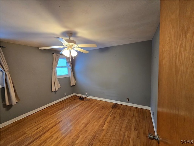 empty room featuring ceiling fan, wood finished floors, and baseboards