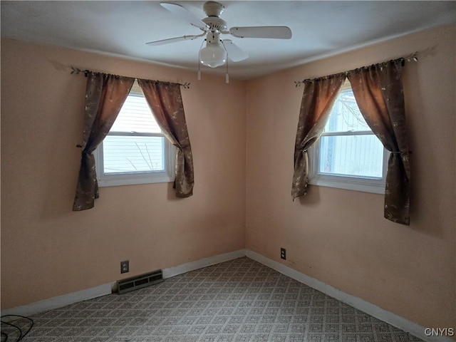 empty room featuring a wealth of natural light, visible vents, and baseboards