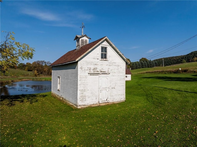 view of outbuilding with a lawn and a water view