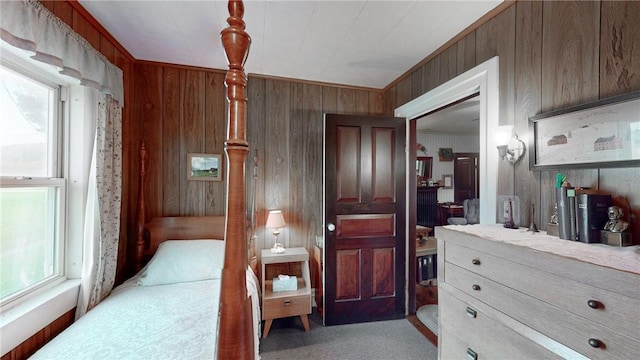 carpeted bedroom with crown molding, wooden walls, and a closet