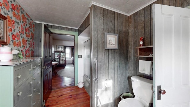 bathroom featuring toilet, crown molding, wooden walls, and hardwood / wood-style flooring