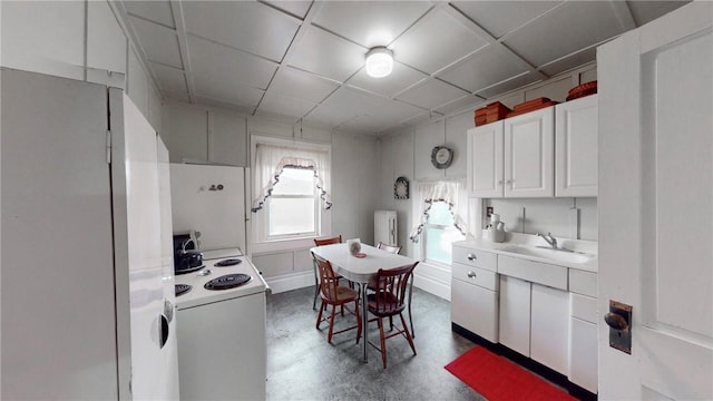 kitchen featuring white appliances, sink, concrete floors, white cabinetry, and radiator heating unit