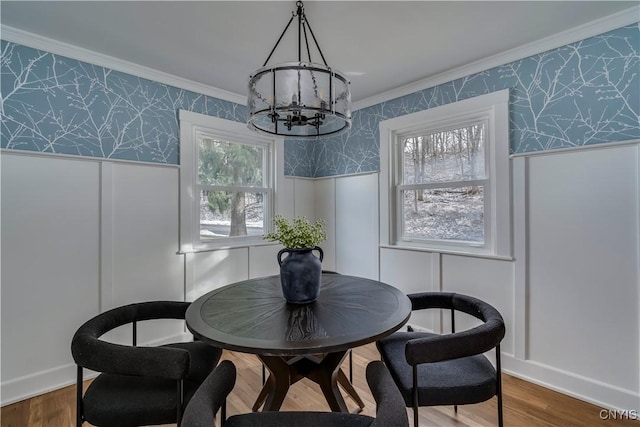 dining room with wood-type flooring, ornamental molding, and an inviting chandelier