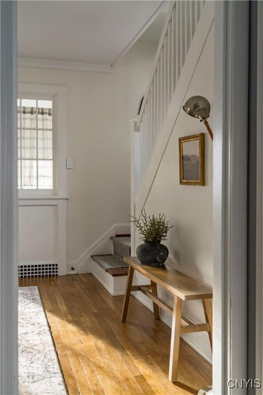 doorway to outside with hardwood / wood-style floors and crown molding