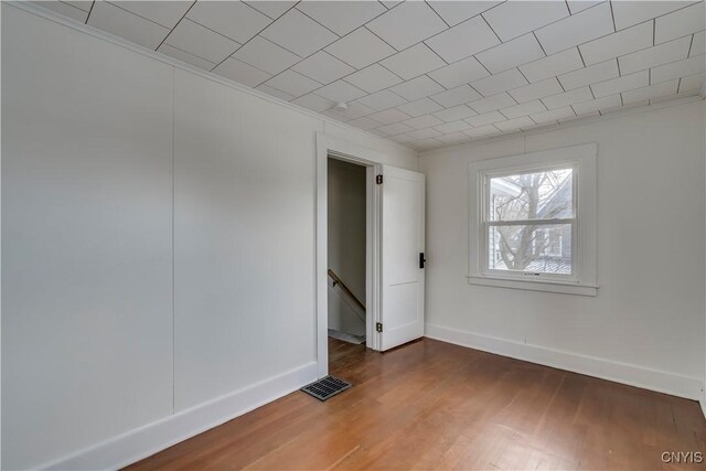 empty room with dark hardwood / wood-style flooring and crown molding