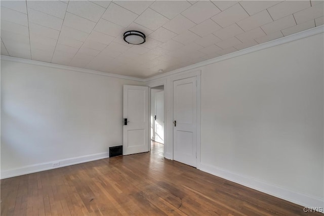 empty room featuring wood-type flooring and crown molding