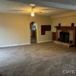 unfurnished living room with ceiling fan and beamed ceiling