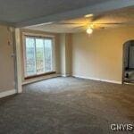 unfurnished living room featuring ceiling fan and beamed ceiling