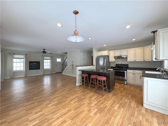 kitchen featuring sink, decorative light fixtures, a breakfast bar, white cabinets, and appliances with stainless steel finishes