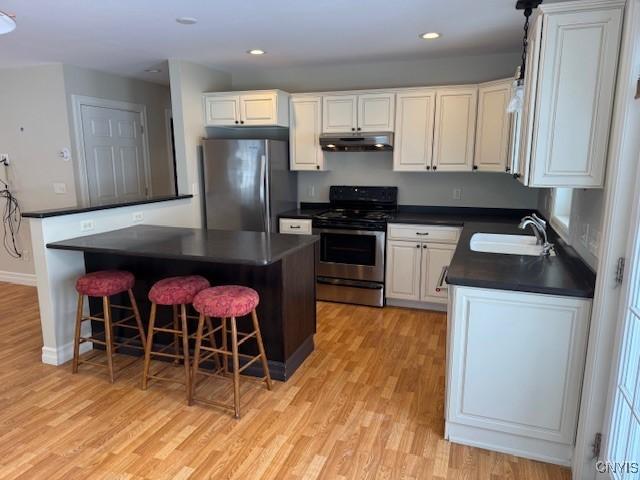 kitchen featuring sink, a center island, a breakfast bar area, white cabinets, and appliances with stainless steel finishes