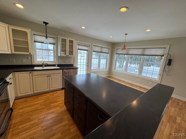 kitchen featuring pendant lighting, stove, sink, and light hardwood / wood-style flooring