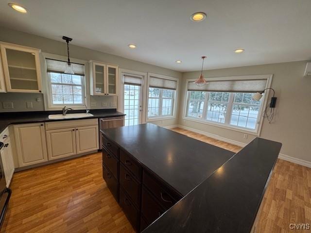 kitchen with pendant lighting, light hardwood / wood-style floors, stainless steel dishwasher, and sink