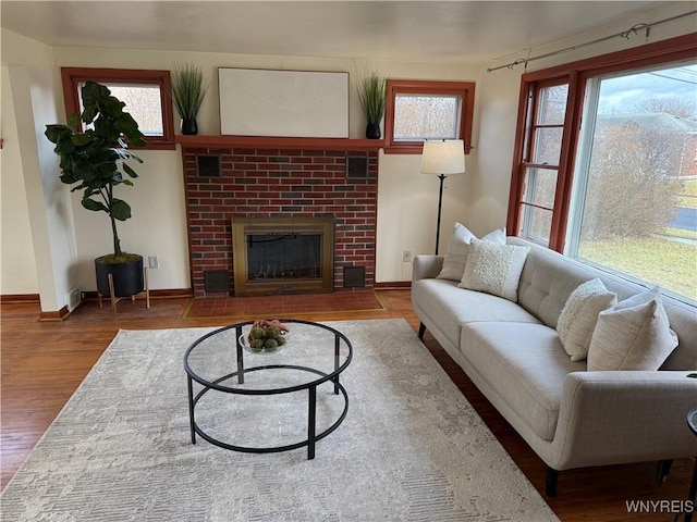 living room featuring wood-type flooring and a brick fireplace