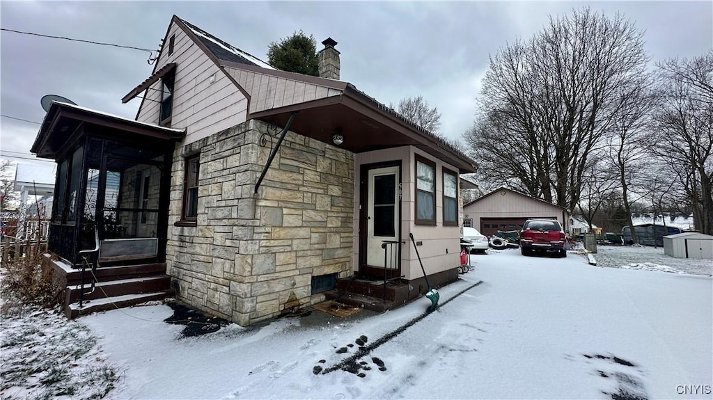 snow covered property with a garage and an outbuilding