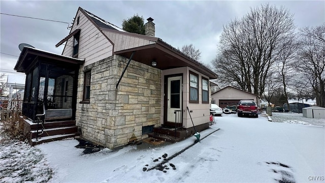 snow covered property with a garage and an outbuilding