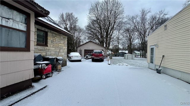 yard layered in snow with a garage and a shed