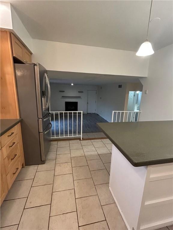 kitchen featuring stainless steel refrigerator with ice dispenser, hanging light fixtures, and light tile patterned flooring