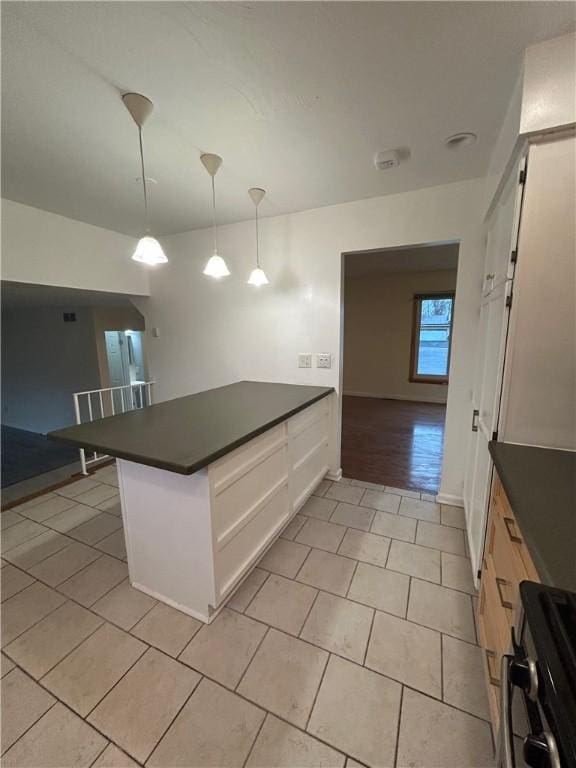 kitchen with white cabinetry, hanging light fixtures, light tile patterned floors, and range