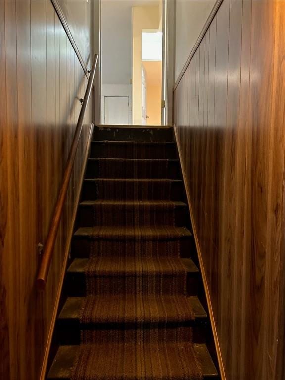 staircase featuring wooden walls