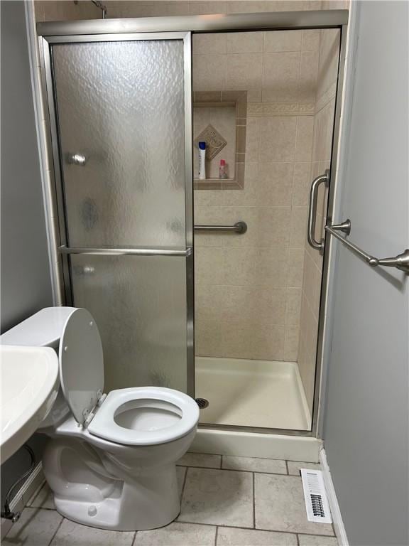 bathroom with tile patterned flooring, an enclosed shower, and toilet