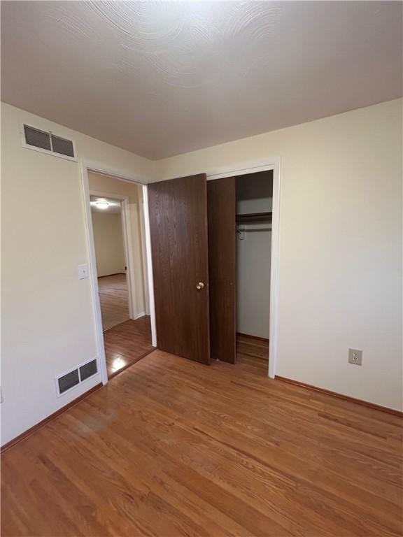 unfurnished bedroom featuring a closet and hardwood / wood-style flooring