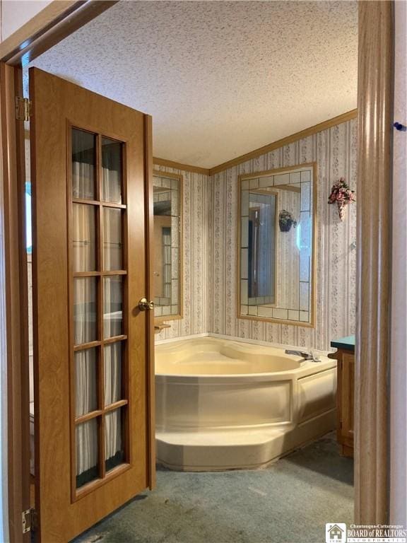 bathroom with a washtub, vanity, a textured ceiling, and ornamental molding