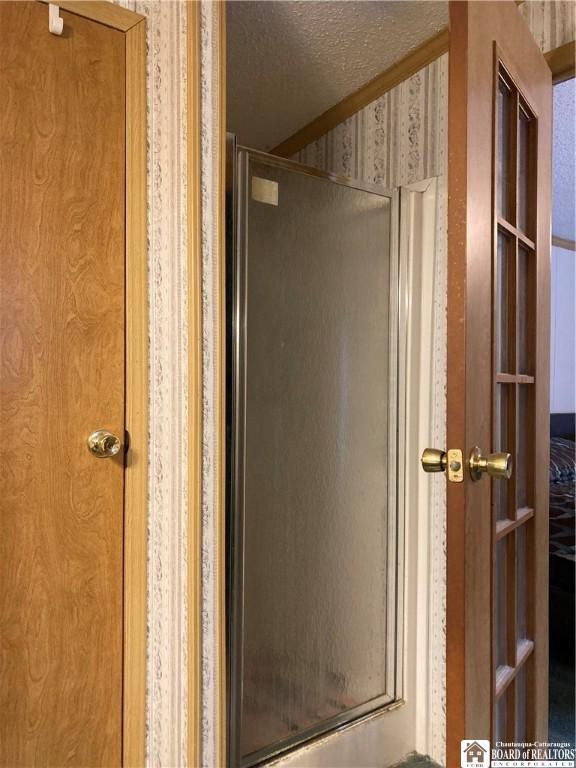 bathroom featuring a shower with door and a textured ceiling