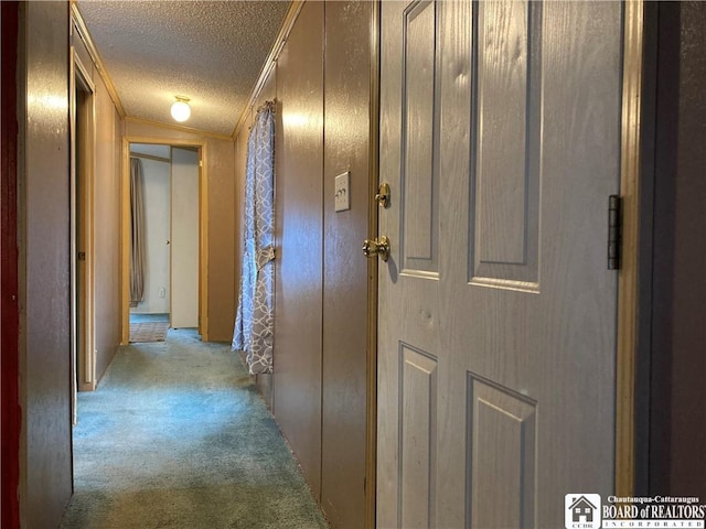 corridor with a textured ceiling, light colored carpet, vaulted ceiling, and ornamental molding