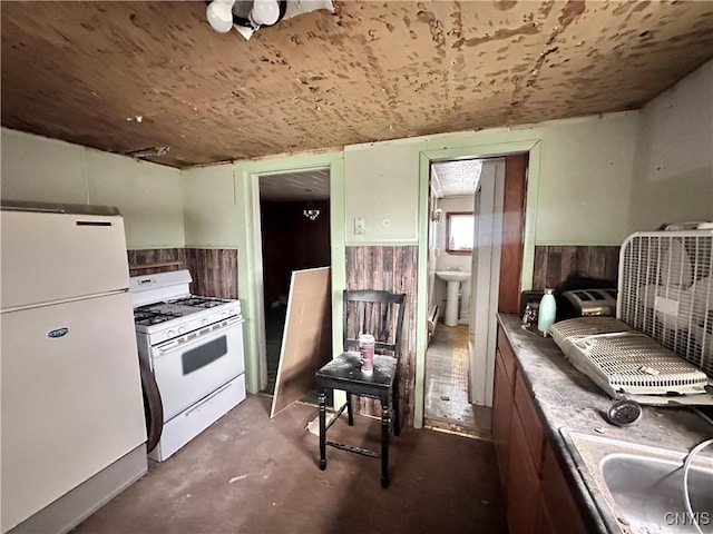 kitchen featuring sink, white appliances, wooden ceiling, and wood walls