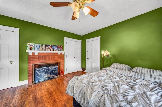 bedroom featuring a fireplace, hardwood / wood-style floors, a textured ceiling, and ceiling fan