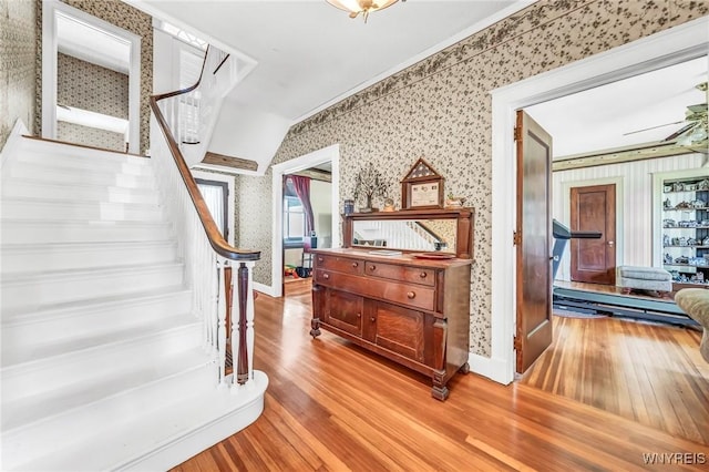 staircase featuring wood-type flooring and ornamental molding