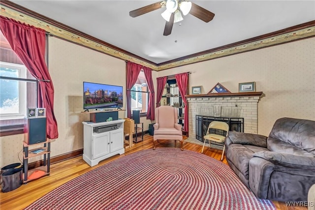 living room featuring crown molding, a fireplace, a healthy amount of sunlight, and light hardwood / wood-style flooring