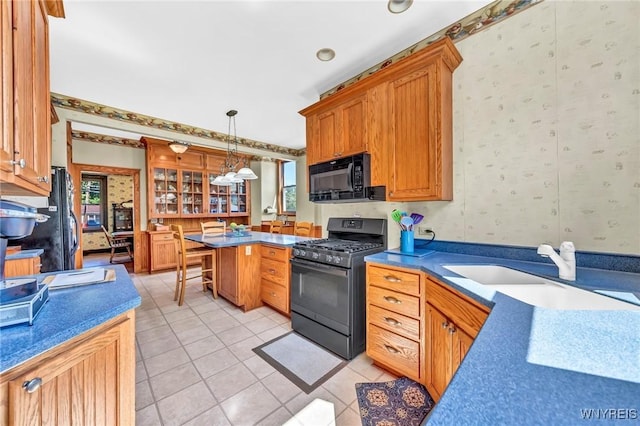 kitchen featuring pendant lighting, black appliances, sink, light tile patterned floors, and a wealth of natural light