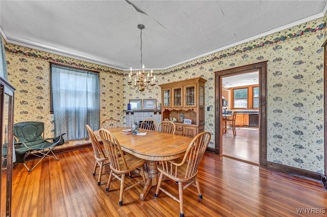 dining space with a chandelier, ornamental molding, a textured ceiling, and dark wood-type flooring