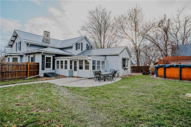 rear view of house with a patio area, a sunroom, a yard, and a covered pool