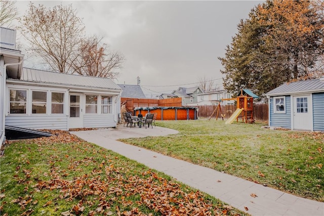 view of yard featuring a patio, a playground, and a sunroom