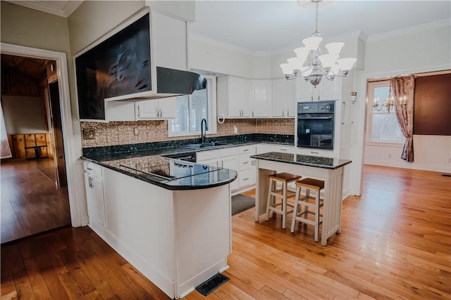 kitchen featuring decorative light fixtures, white cabinetry, sink, and a wealth of natural light