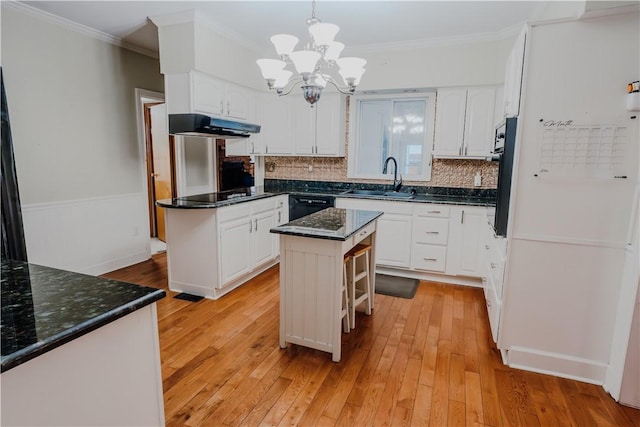 kitchen with a center island, sink, light hardwood / wood-style floors, pendant lighting, and white cabinets