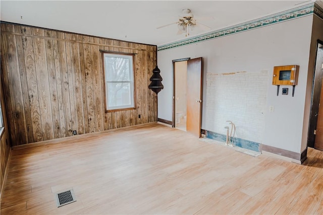 unfurnished room featuring ceiling fan, wooden walls, and hardwood / wood-style flooring