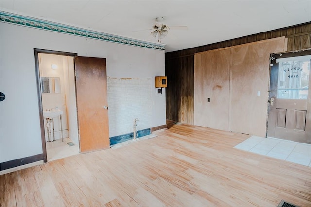 entryway with ceiling fan, sink, wood walls, and light wood-type flooring