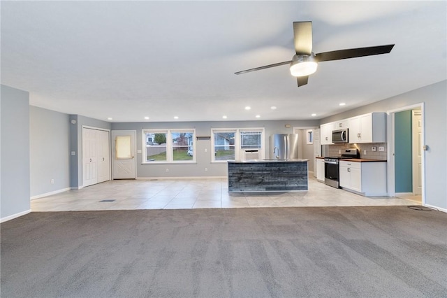 unfurnished living room featuring ceiling fan, sink, and light carpet