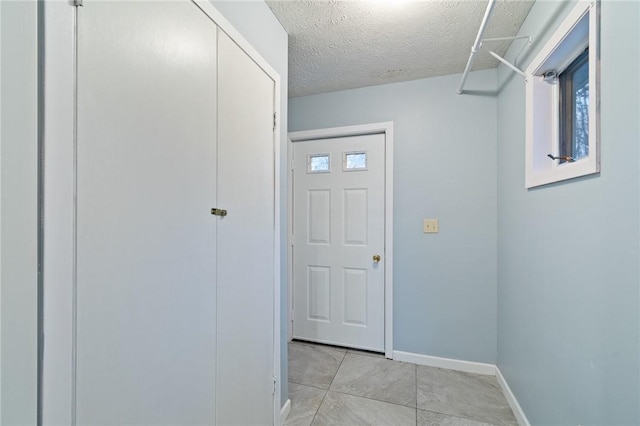 corridor with light tile patterned floors and a textured ceiling