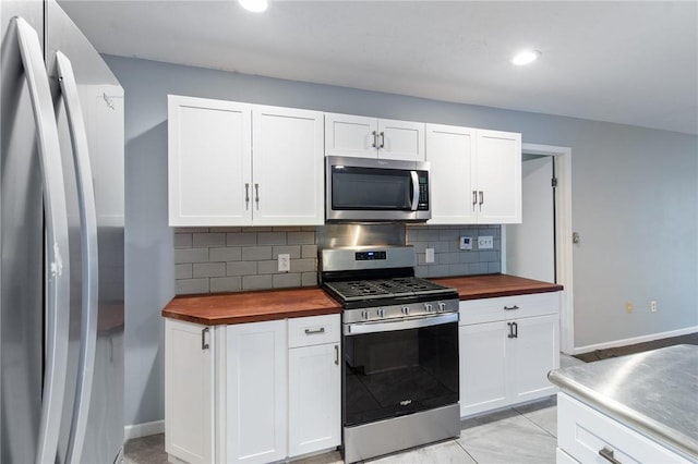 kitchen featuring butcher block countertops, decorative backsplash, white cabinetry, and appliances with stainless steel finishes