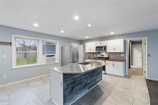 kitchen featuring sink, stainless steel appliances, tasteful backsplash, a center island with sink, and white cabinets