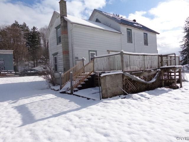 snow covered back of property featuring a deck