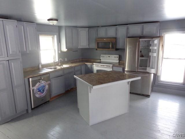 kitchen with white range with electric cooktop, sink, stainless steel fridge, a kitchen island, and washer / clothes dryer