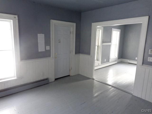 unfurnished room with a healthy amount of sunlight and a baseboard heating unit