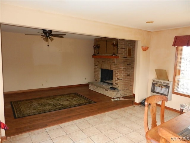 living room with ceiling fan, heating unit, light hardwood / wood-style floors, and a brick fireplace