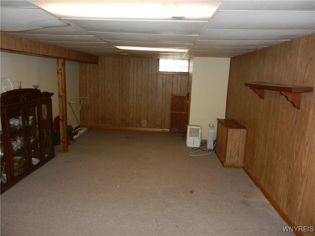 basement featuring light colored carpet and wood walls