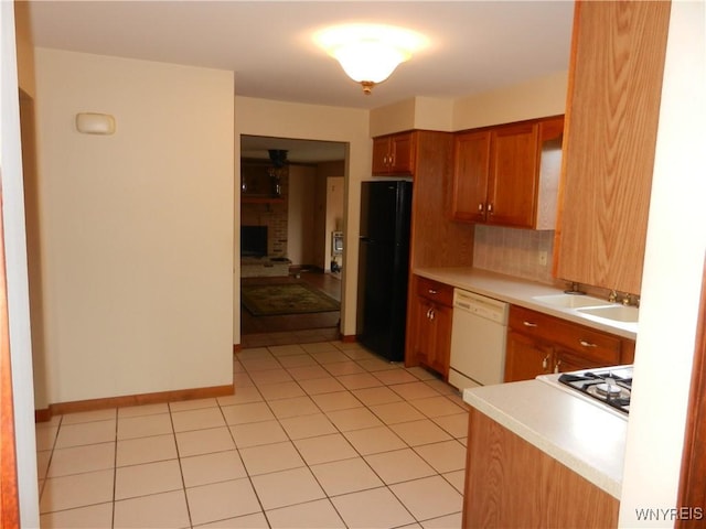 kitchen with a brick fireplace, decorative backsplash, white appliances, light tile patterned flooring, and sink